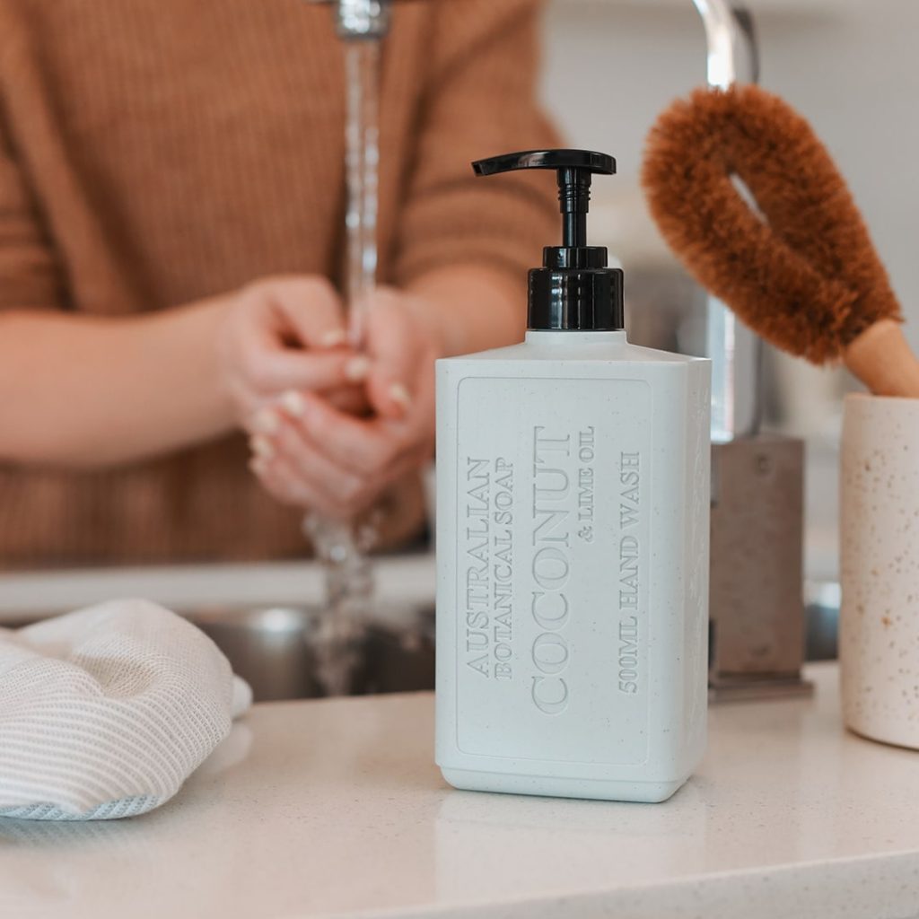 coconut hand soap in front of someone washing their hands 
